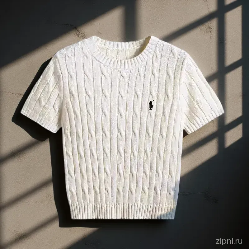 Свитер cable knit на фоне бетонной стены, освещенный направленным солнечным светом.